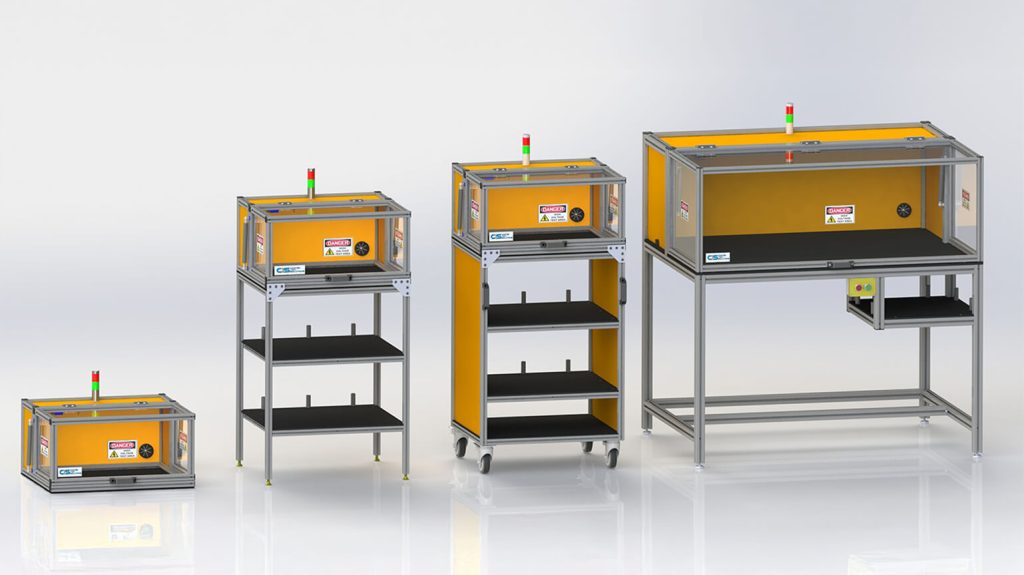 Four industrial safety enclosures of different sizes with aluminum frames and signal lights.